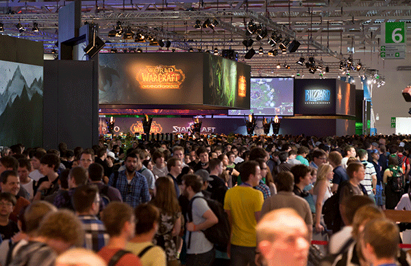 Dav návštevníkov na veľtrhu Gamescom 2011 v Kolíne nad Rýnom, pod veľkoplošnými obrazovkami a stánkami vystavovateľov z videoherného priemyslu.