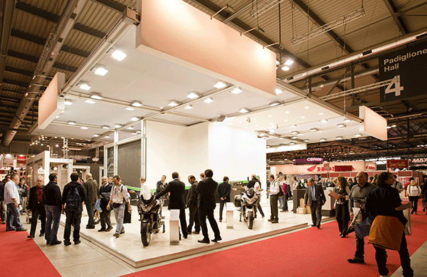 Návštevníci a vystavovatelia komunikujú pri stánkoch na medzinárodnom veľtrhu v modernej výstavnej hale.